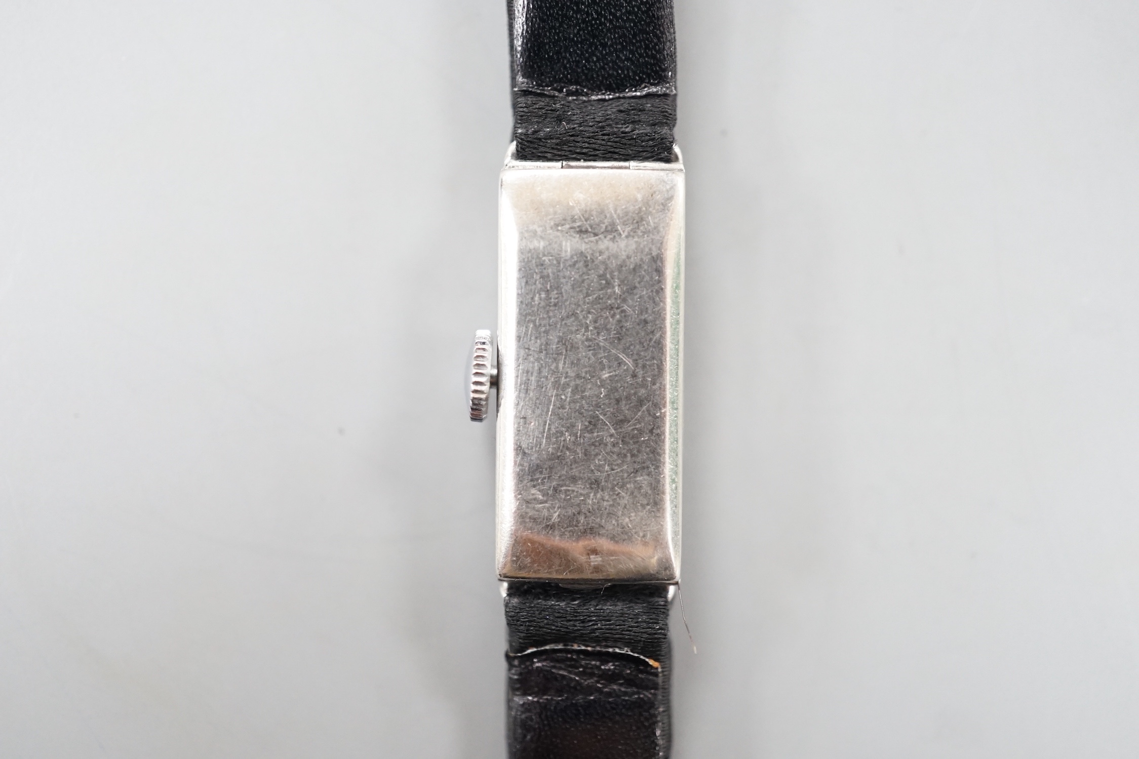 A lady's white meat (stamped Platinum) and diamond set rectangular manual wind cocktail watch, case diameter 11mm, on a black fabric strap, gross weight 10.3 grams.